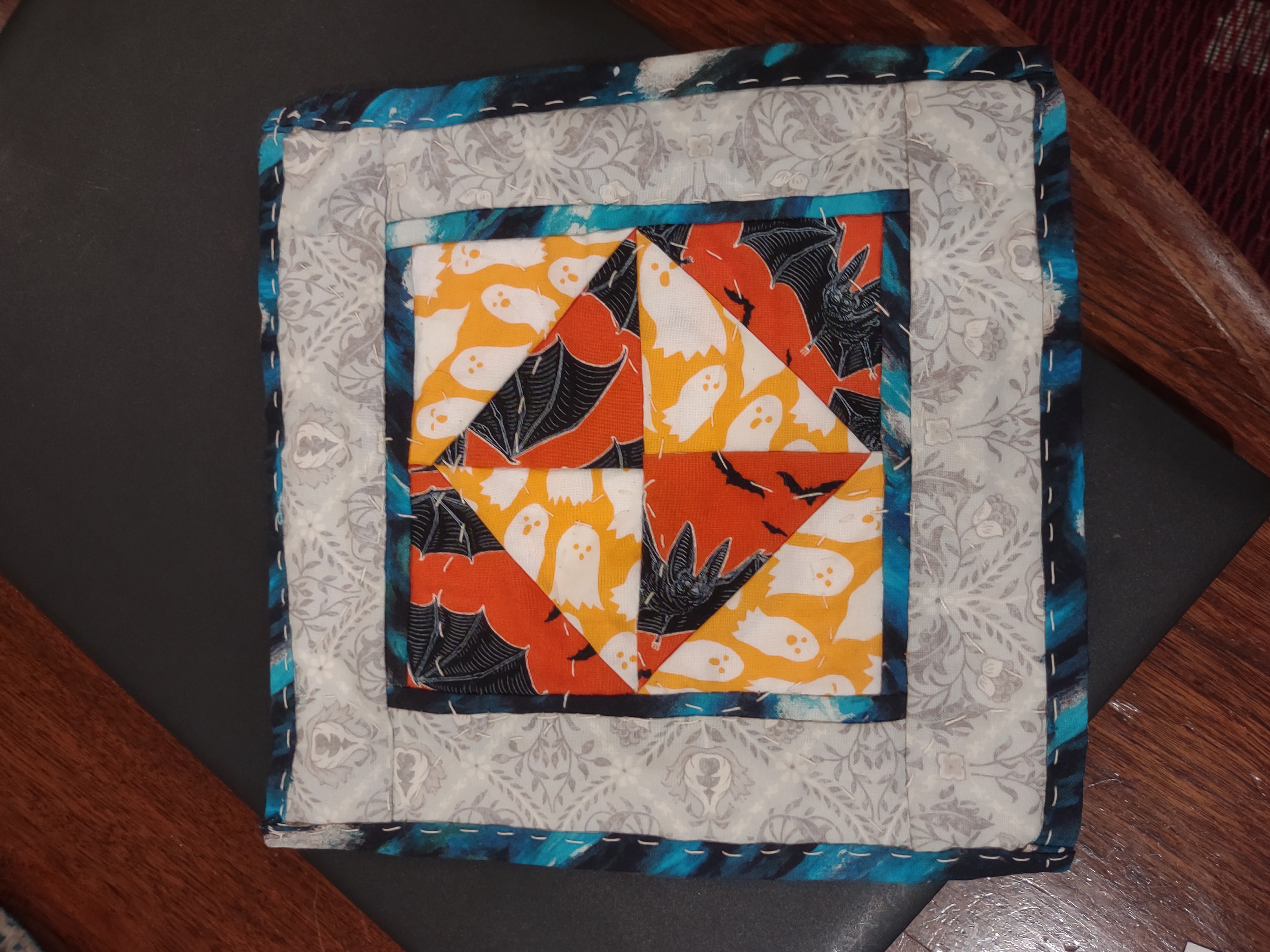 quilt square with orange ghosts and bats fabrics bordered with blue and grey