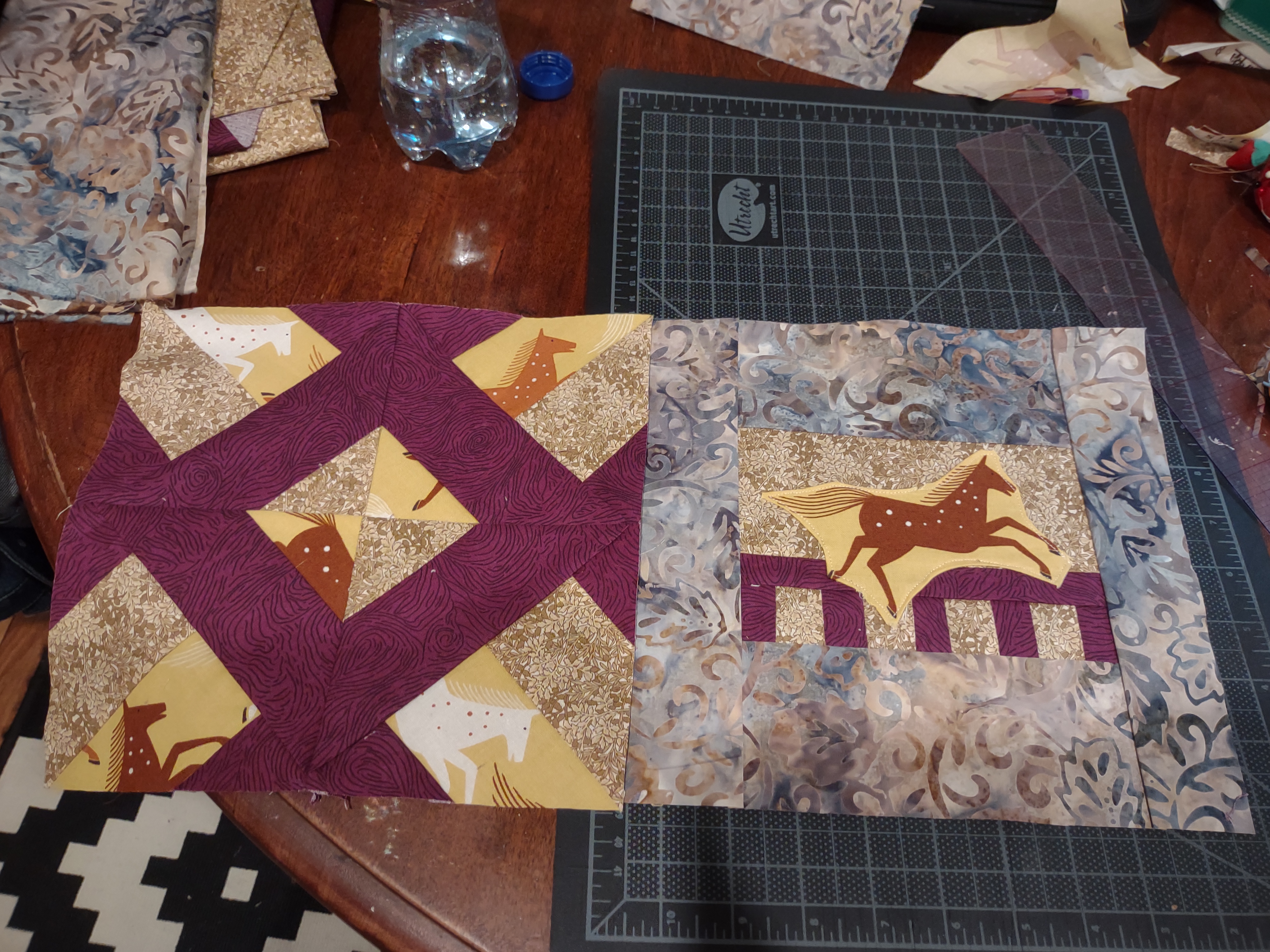 two connected quilt squares. one is a hidden wells block with purple woodgrain and horse fabric. The other is an applique block with a horse leaping out of a purple fence.